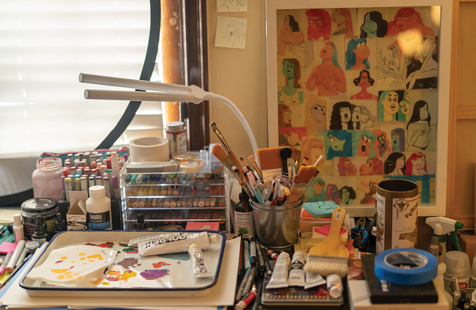 Artists's desk with Post-it Note paintings on the wall.