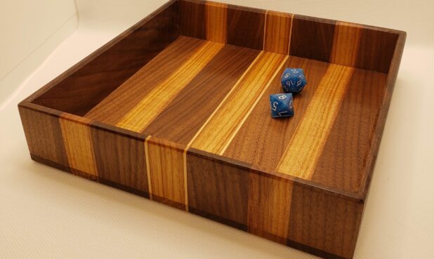 TITLE: CANARY-WOOD DICE TRAY SIZE: 9" x 9" x 2" DESCRIPTION: Made from exotic canary, hard maple, and walnut woods to keep your dice rolls contained to the tabletop. Finished with a glossy coat of shellac. PRICE: $50