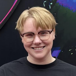 Person with short blonde hair and glasses