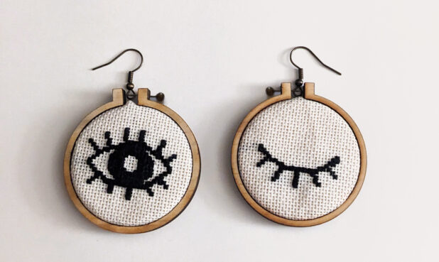 TITLE: CROSS STITCH HOOP EARRINGS SIZE: 1.75” diameter DESCRIPTION: Hoop with a hand cross-stitch image. Hoop is lightweight, laser-cut plywood.PRICE: $40 (per pair)